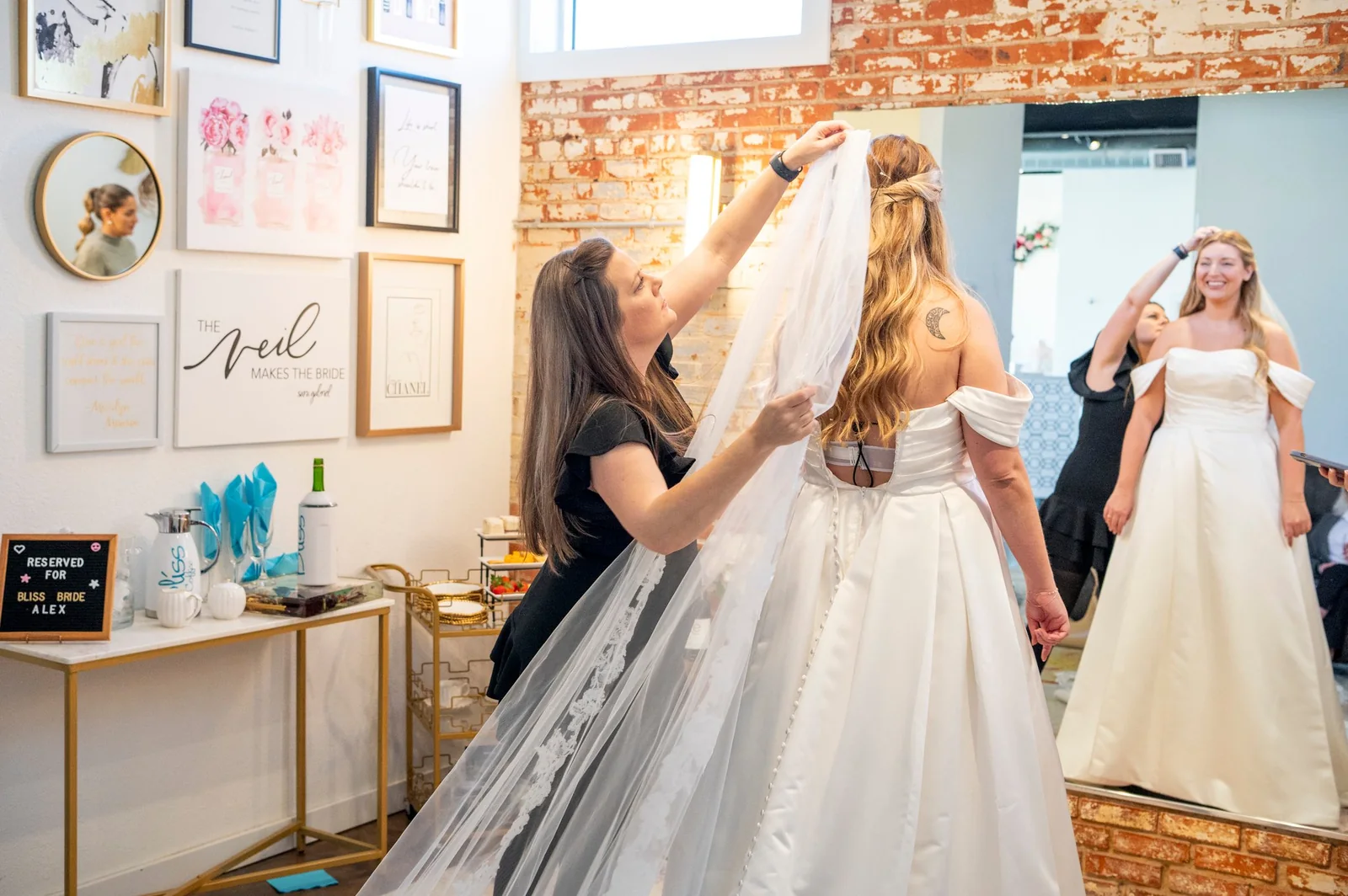 A Bliss Bridal stylist placing a veil on a bride in the salon, Fort Worth